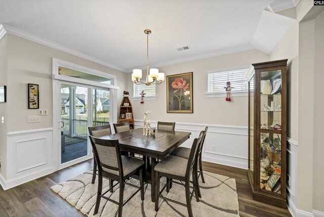 dining space featuring dark hardwood / wood-style flooring, crown molding, and a chandelier