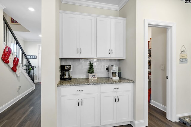 bar with dark wood-type flooring, stone countertops, crown molding, backsplash, and white cabinets