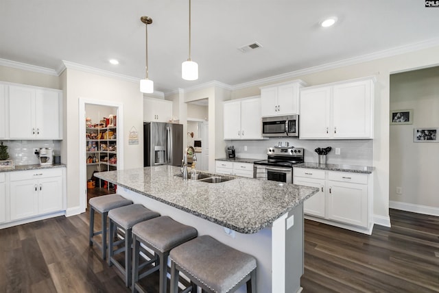 kitchen with appliances with stainless steel finishes, hanging light fixtures, light stone counters, and sink