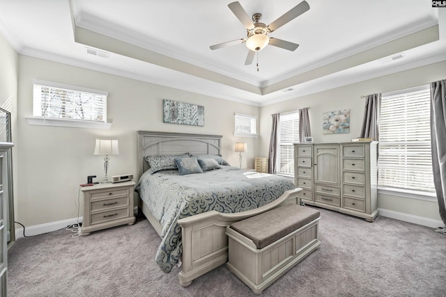 carpeted bedroom featuring a raised ceiling, ceiling fan, multiple windows, and crown molding