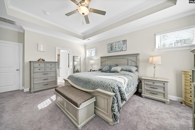 carpeted bedroom with ensuite bathroom, ceiling fan, a tray ceiling, and ornamental molding