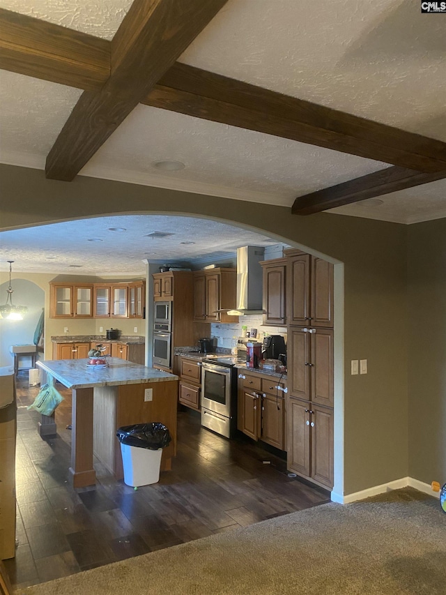 kitchen featuring a kitchen island, stainless steel appliances, a textured ceiling, and wall chimney range hood