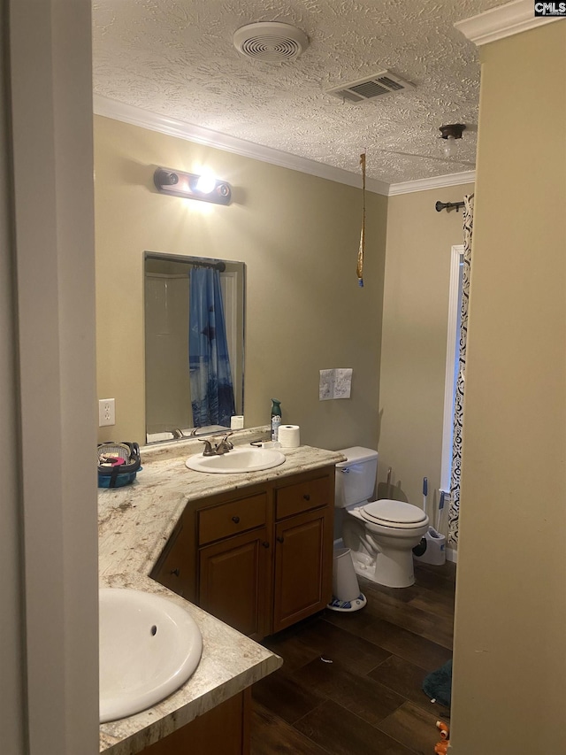 bathroom featuring a textured ceiling, hardwood / wood-style flooring, toilet, vanity, and crown molding