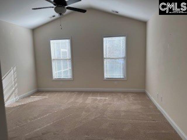 unfurnished room with ceiling fan, vaulted ceiling, a wealth of natural light, and light carpet