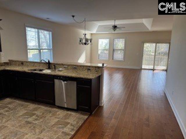 kitchen with sink, dishwasher, light hardwood / wood-style floors, ceiling fan with notable chandelier, and light stone countertops