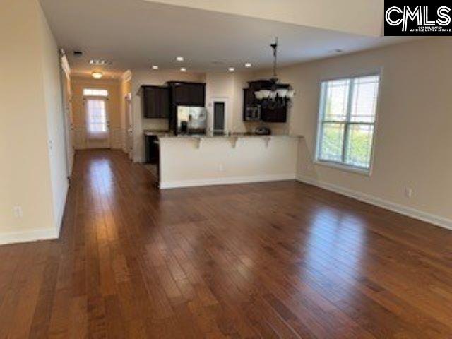 kitchen with a chandelier, kitchen peninsula, a breakfast bar, dark wood-type flooring, and fridge