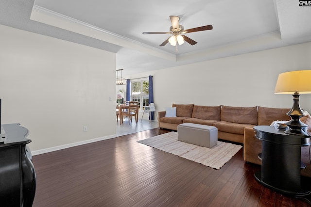 living room featuring ceiling fan, dark wood-type flooring, crown molding, and a tray ceiling