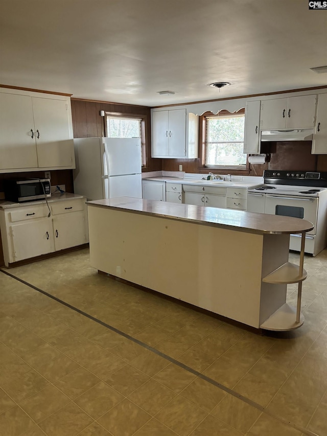 kitchen featuring white appliances, white cabinets, a kitchen island, and sink