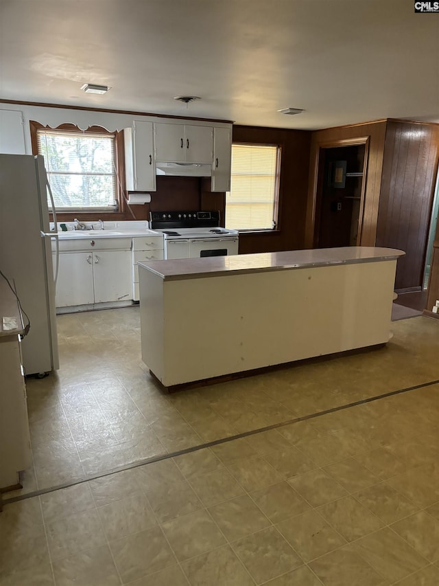 kitchen featuring white appliances, white cabinets, a kitchen island, and sink