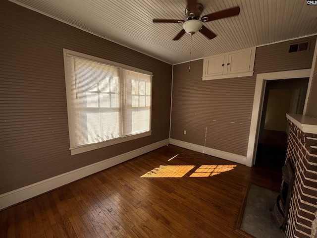 unfurnished room featuring wooden walls, a fireplace, ceiling fan, and dark wood-type flooring