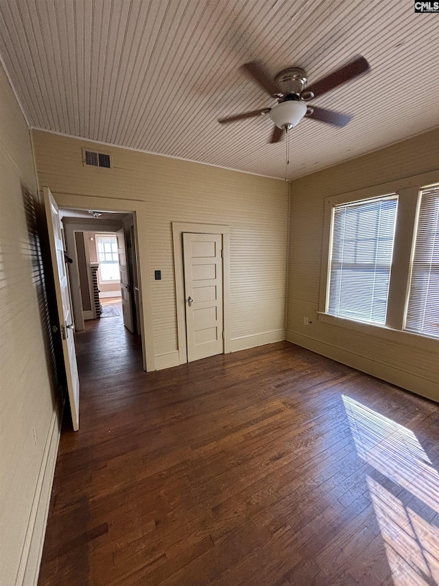 unfurnished room featuring baseboard heating, ceiling fan, and dark hardwood / wood-style floors