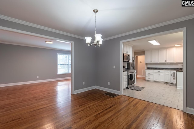 interior space featuring stainless steel appliances, white cabinets, an inviting chandelier, light hardwood / wood-style flooring, and hanging light fixtures