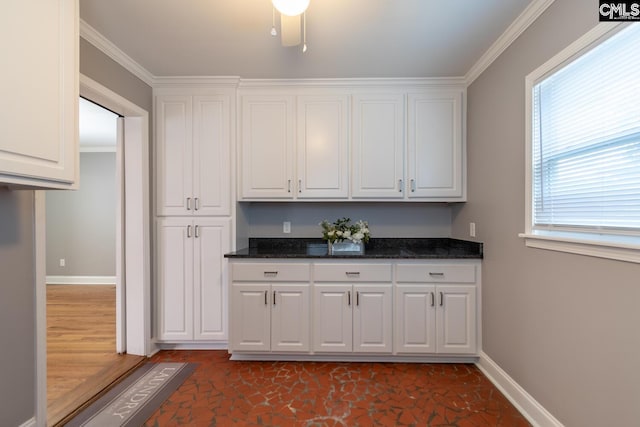 kitchen with ornamental molding, dark stone countertops, and white cabinetry