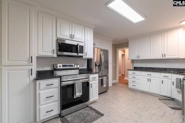 kitchen with appliances with stainless steel finishes, white cabinetry, ornamental molding, and backsplash