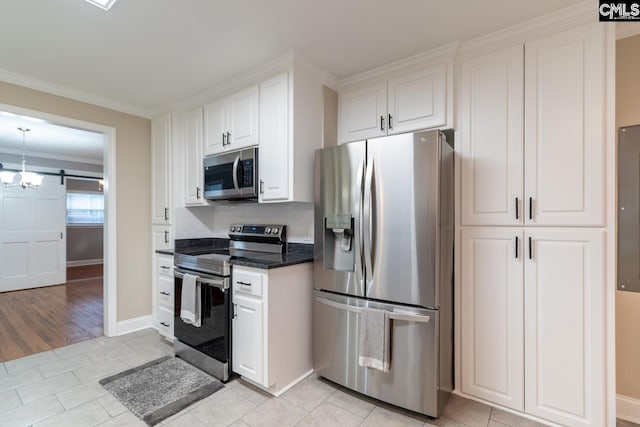 kitchen featuring stainless steel appliances, white cabinetry, light tile patterned flooring, a barn door, and crown molding