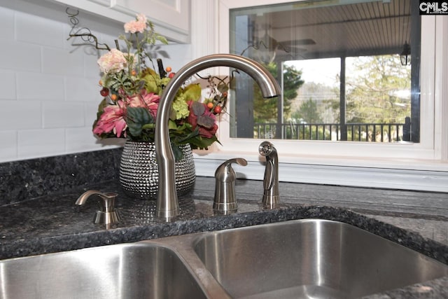 interior details with sink, decorative backsplash, and dark stone countertops