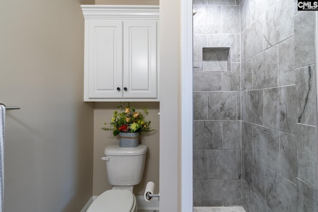 bathroom with a tile shower and toilet