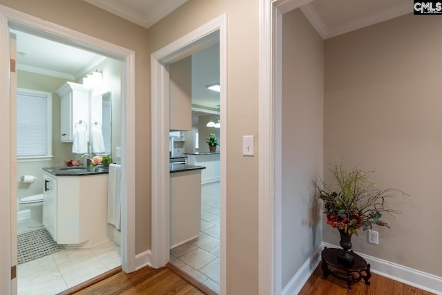 hall with sink, light wood-type flooring, and crown molding