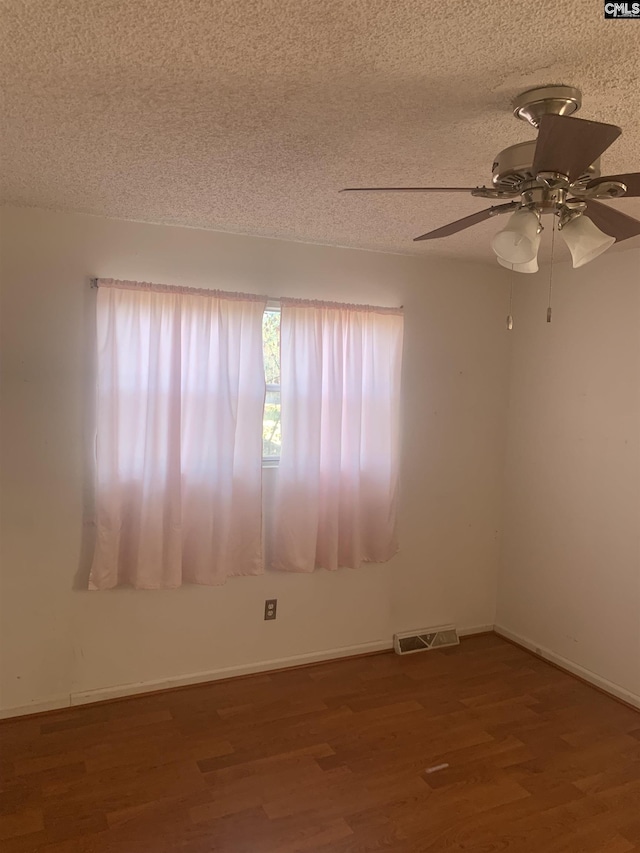 unfurnished room with dark wood-type flooring, a textured ceiling, and ceiling fan