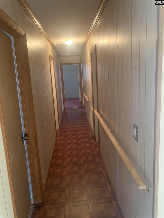 hall with dark parquet flooring, ornamental molding, and wooden walls