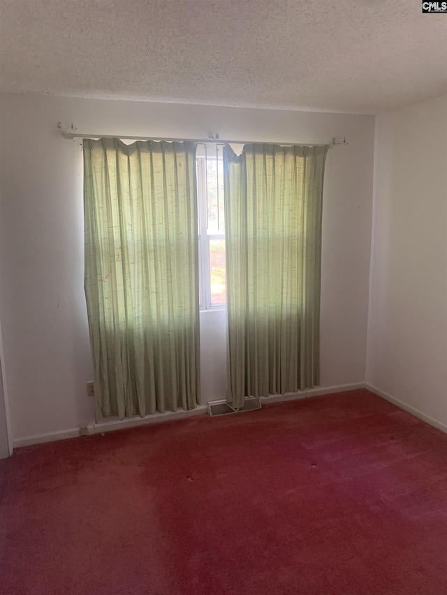 carpeted empty room with a textured ceiling