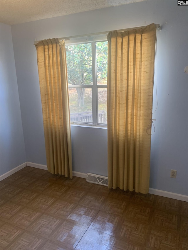 spare room featuring dark parquet flooring and a textured ceiling