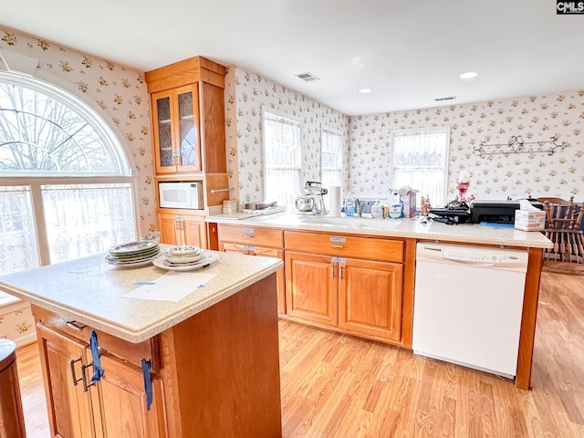 kitchen with white appliances, light hardwood / wood-style flooring, a center island, and sink