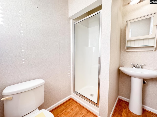 bathroom with toilet, a shower with shower door, and hardwood / wood-style flooring