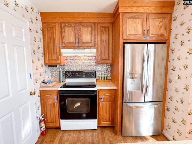 kitchen featuring stainless steel refrigerator with ice dispenser, light hardwood / wood-style floors, and electric range oven