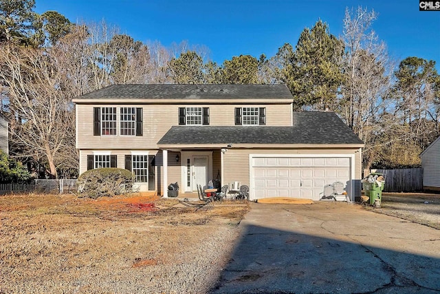 traditional home featuring driveway, an attached garage, and fence