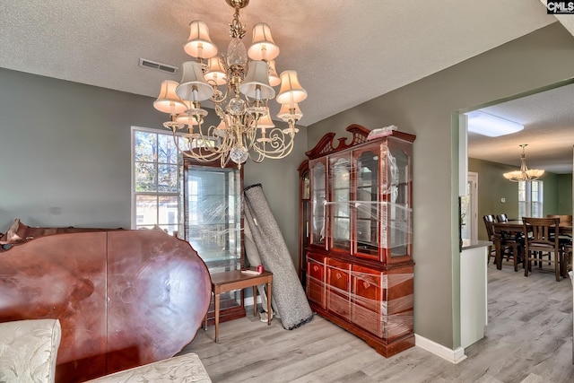 dining area featuring a textured ceiling, light wood-type flooring, and an inviting chandelier