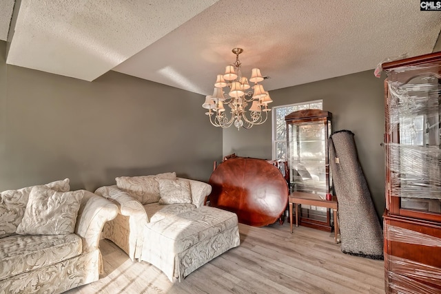 sitting room with an inviting chandelier, light wood-type flooring, and a textured ceiling