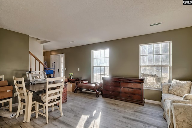 dining area featuring a textured ceiling, a healthy amount of sunlight, and light hardwood / wood-style flooring