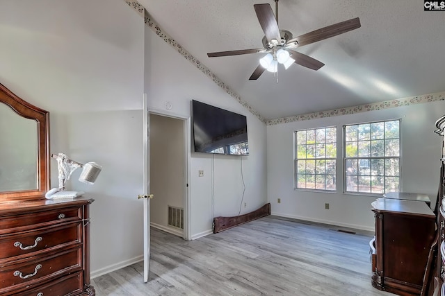 bedroom with ceiling fan, light hardwood / wood-style flooring, lofted ceiling, and a textured ceiling