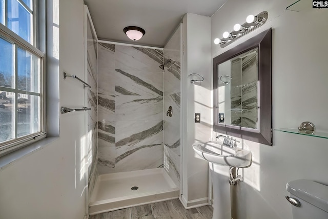 bathroom featuring toilet, tiled shower, and hardwood / wood-style flooring