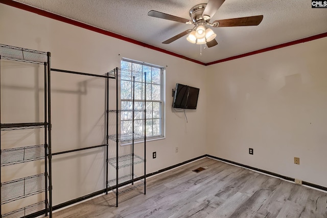 unfurnished bedroom featuring a textured ceiling, ceiling fan, crown molding, and light wood-type flooring