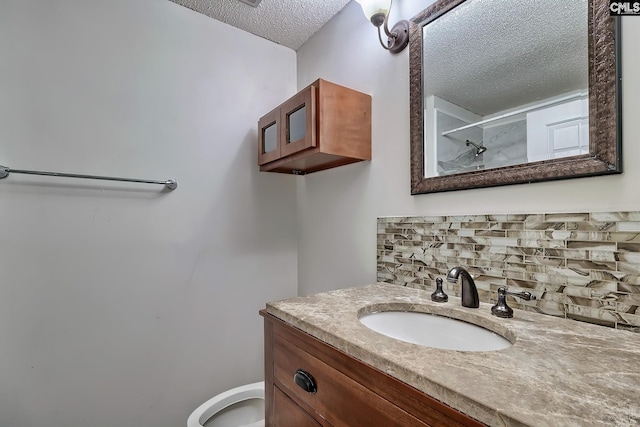 bathroom featuring toilet, a textured ceiling, tasteful backsplash, and vanity