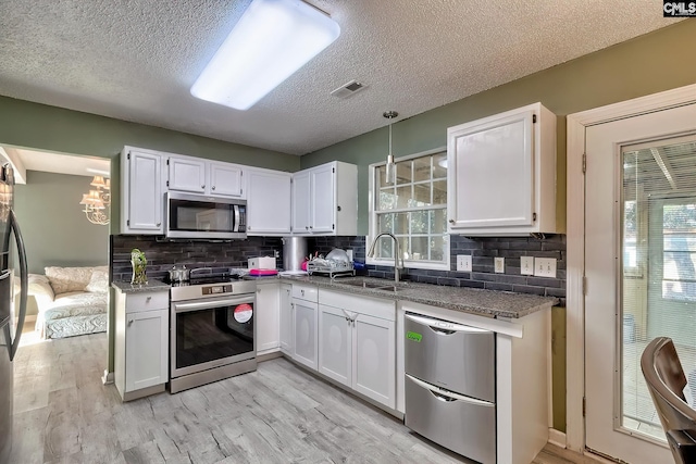 kitchen with stainless steel appliances, white cabinets, sink, and backsplash