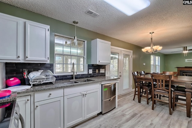 kitchen with tasteful backsplash, hanging light fixtures, a textured ceiling, white cabinets, and sink