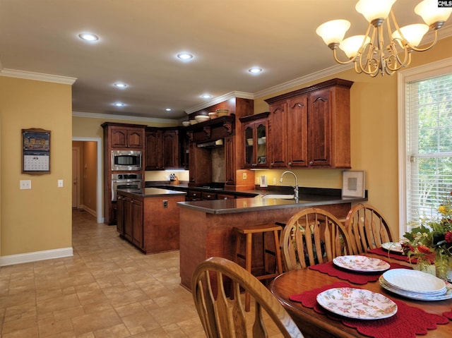 kitchen with a chandelier, appliances with stainless steel finishes, hanging light fixtures, kitchen peninsula, and sink