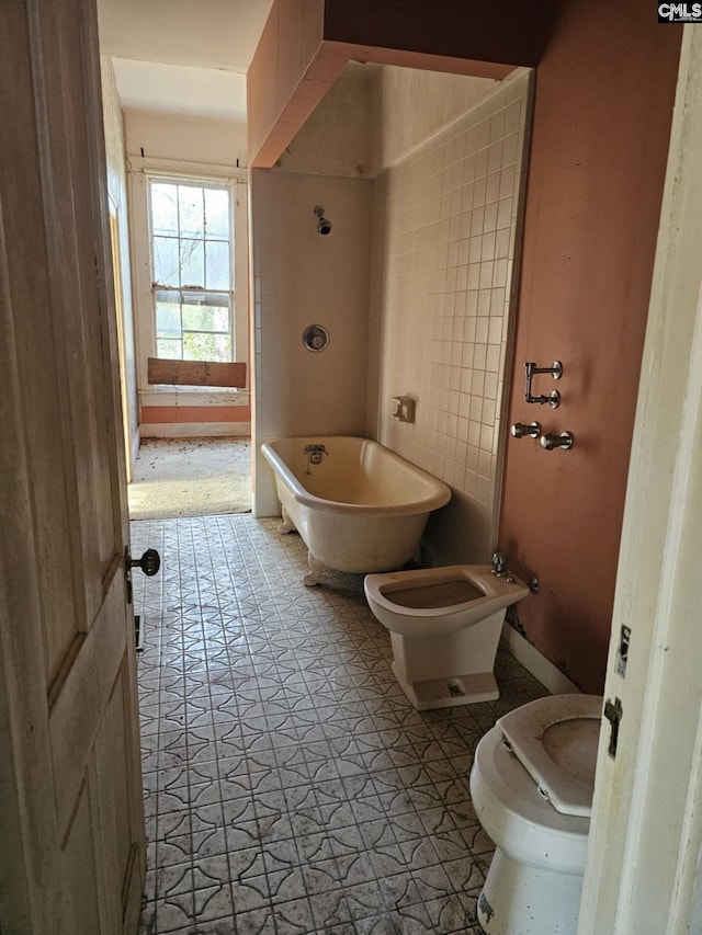 bathroom with a bath, a bidet, tile patterned floors, and toilet