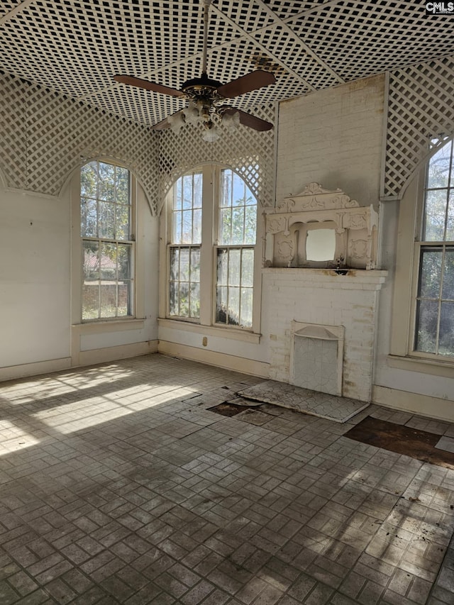 unfurnished living room featuring a brick fireplace and ceiling fan