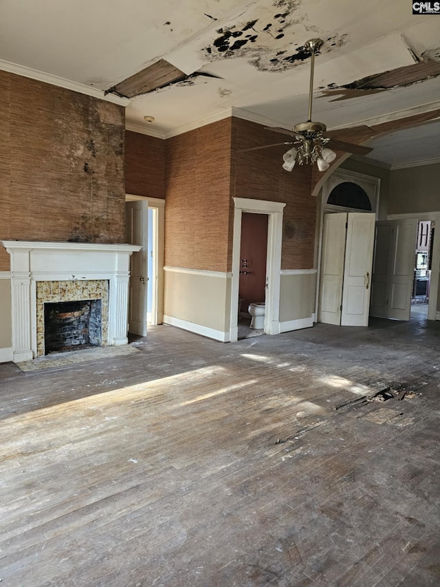 unfurnished living room with ceiling fan, ornamental molding, and a stone fireplace