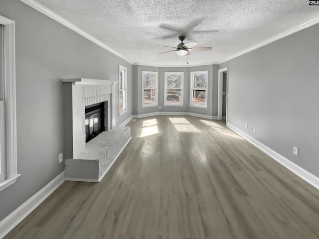 unfurnished living room with ornamental molding, ceiling fan, a brick fireplace, and hardwood / wood-style flooring