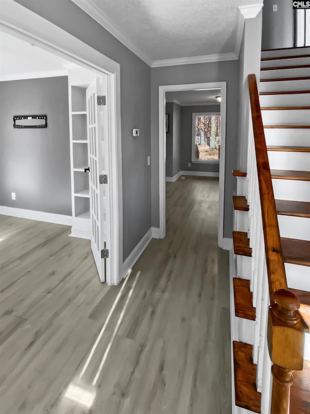 interior space featuring a textured ceiling, crown molding, and wood-type flooring