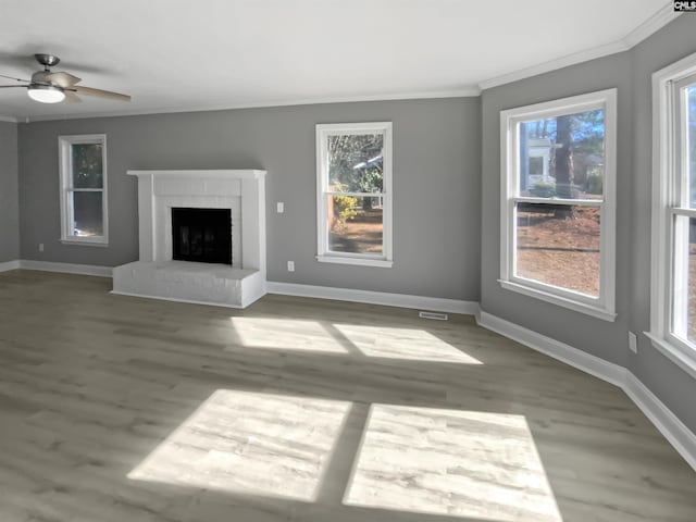 unfurnished living room featuring ceiling fan, a fireplace, ornamental molding, and hardwood / wood-style flooring