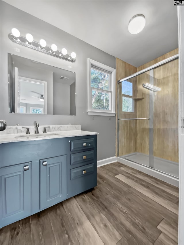 bathroom featuring hardwood / wood-style floors, a shower with door, ceiling fan, and vanity