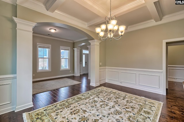 interior space featuring beam ceiling, dark hardwood / wood-style floors, coffered ceiling, ornamental molding, and ornate columns