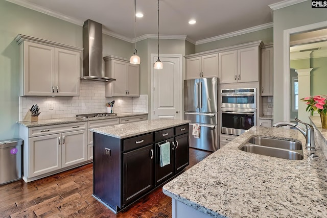 kitchen with sink, hanging light fixtures, a kitchen island, stainless steel appliances, and wall chimney range hood