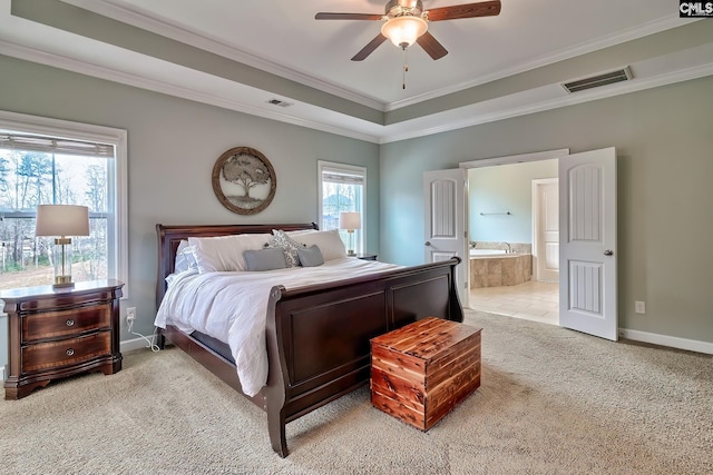 bedroom featuring ensuite bathroom, light colored carpet, ornamental molding, a raised ceiling, and ceiling fan